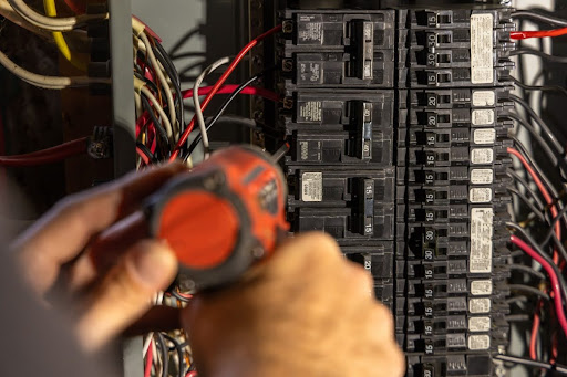 Grasser electrician performing work on circuit breakers.